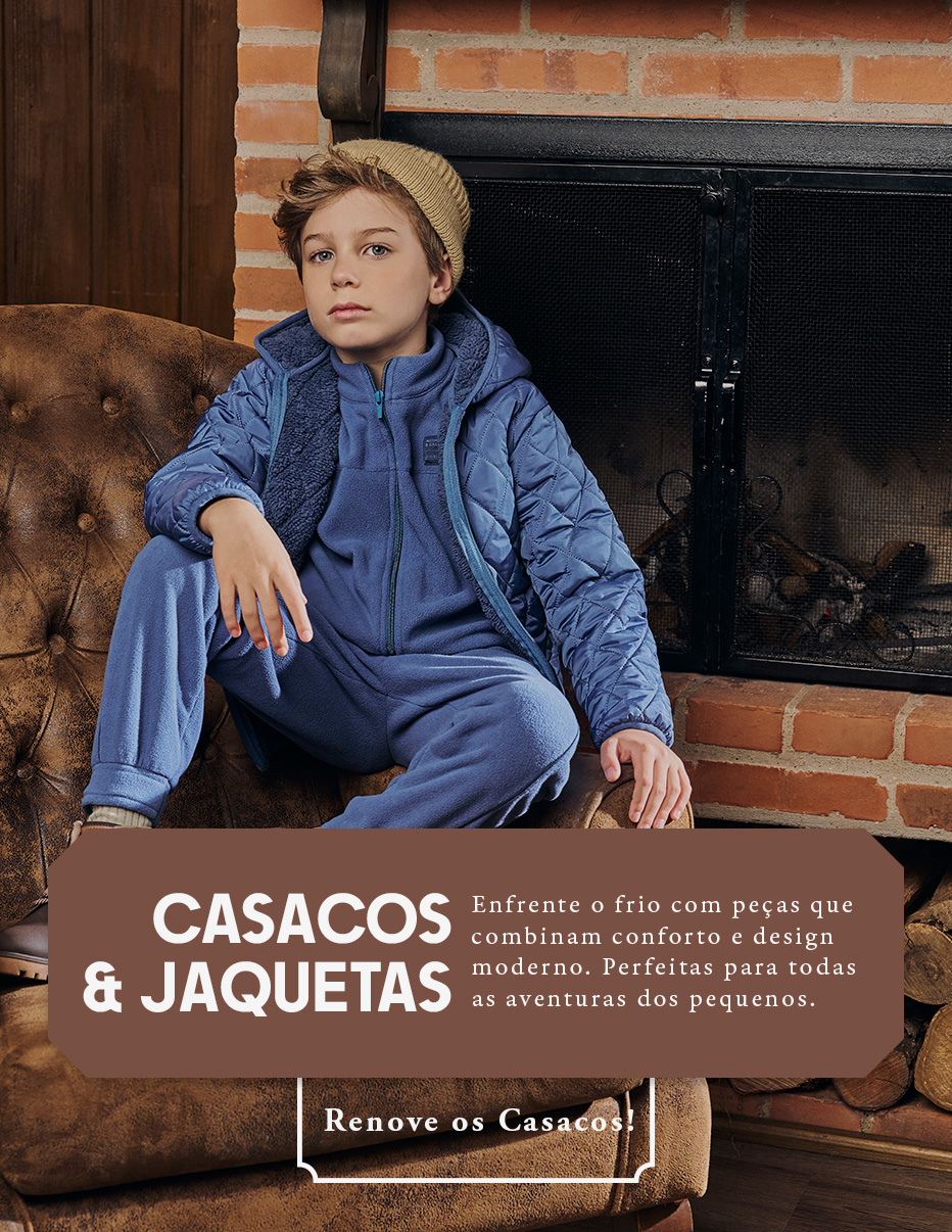 Menino sentado em um sofá de couro próximo à lareira, usando conjunto azul e jaqueta acolchoada com touca, destacando roupas infantis quentes e modernas para o frio.